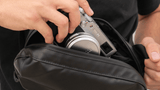 Hand pulling a camera out of a black D1 Fanny