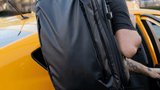 Man getting into a cab wearing the black Transit Travel Backpack 